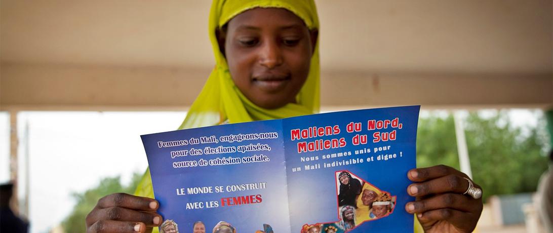 A young woman reads the official informational flyer of the Peace Caravan in Gao, Mali. August, 2013. UN Photo/Marco Dormino.